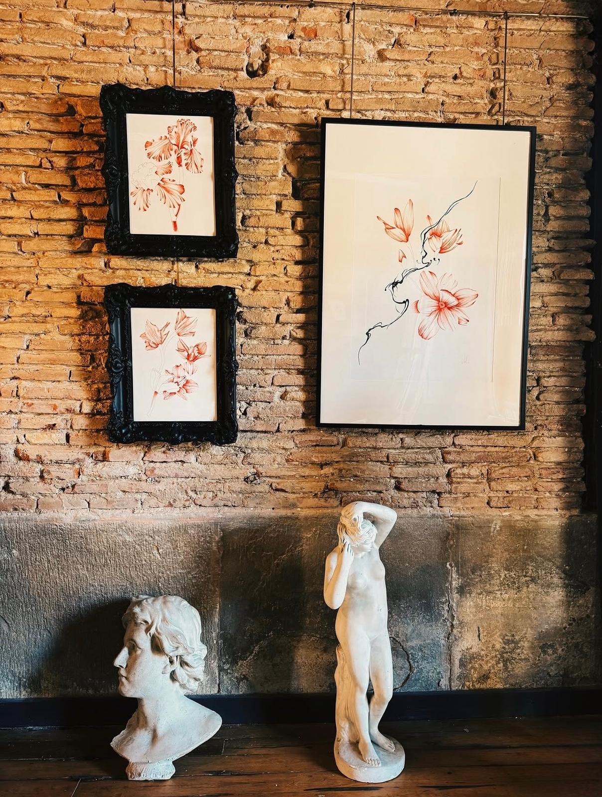 Pared de estudio con ilustraciones florales enmarcadas y esculturas de escayola
