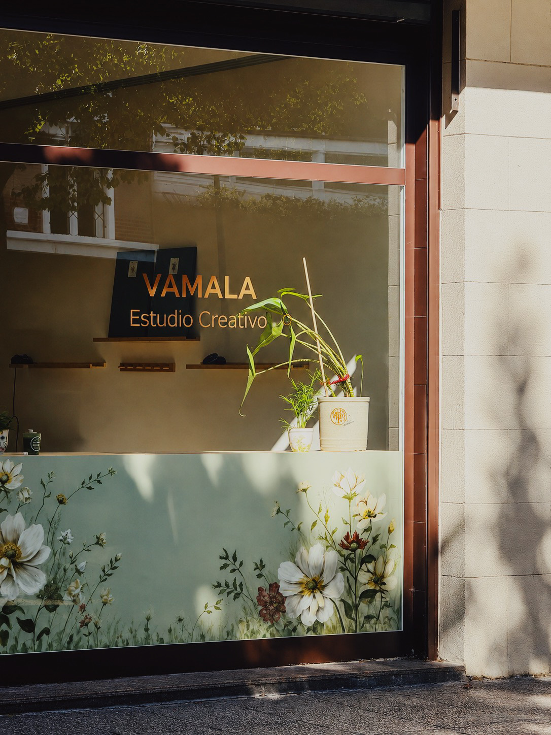 Escaparate del estudio VAMALA desde la calle, con el rótulo y las flores pintadas en el cristal