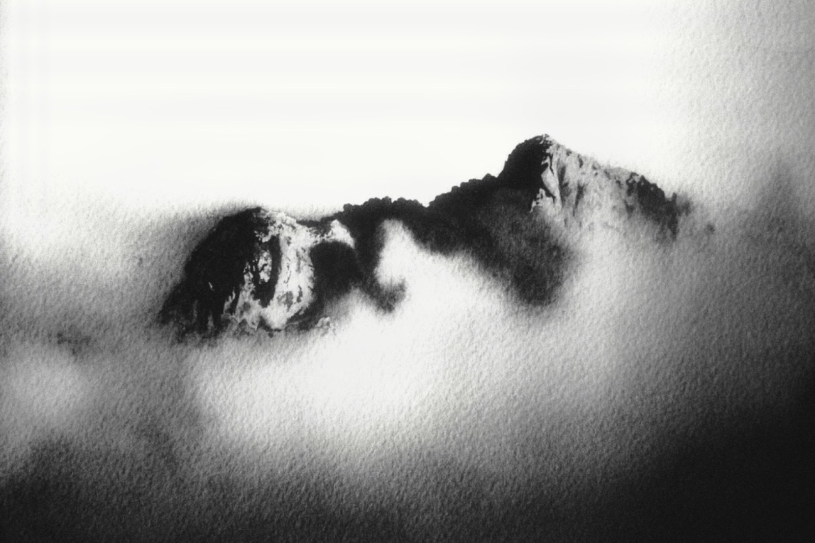 Montaña en blanco y negro emergiendo de la niebla